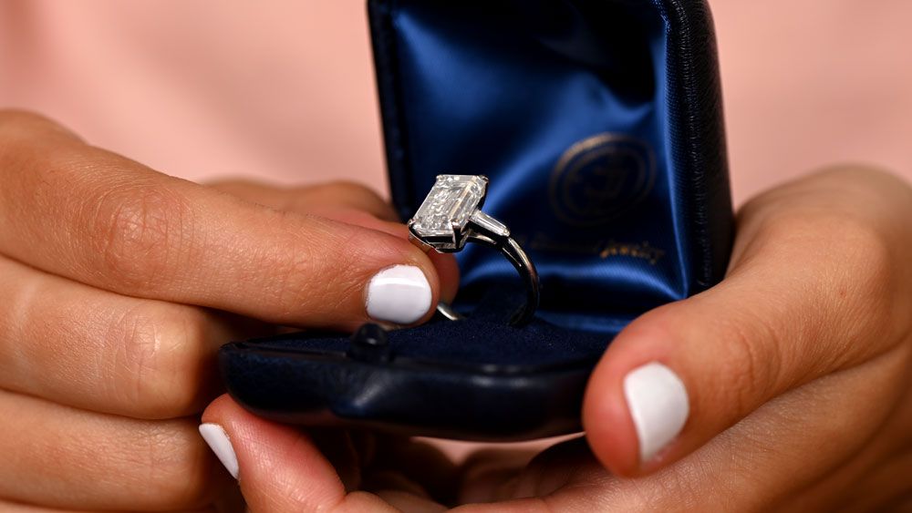 Customer Holding Emerald Cut Diamond Engagement Ring in Showroom